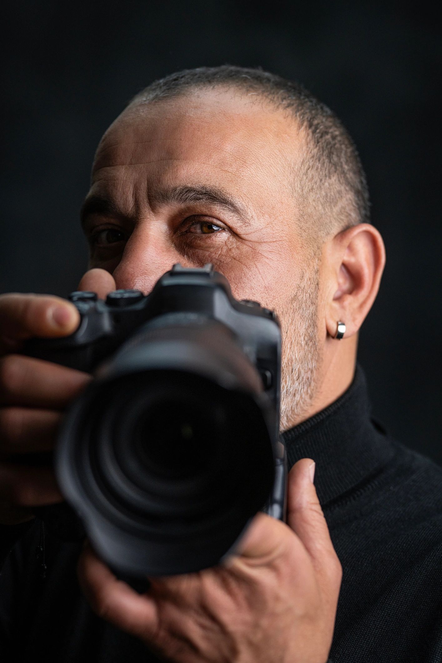 Portrait of the photographer holding a camera in a dark studio